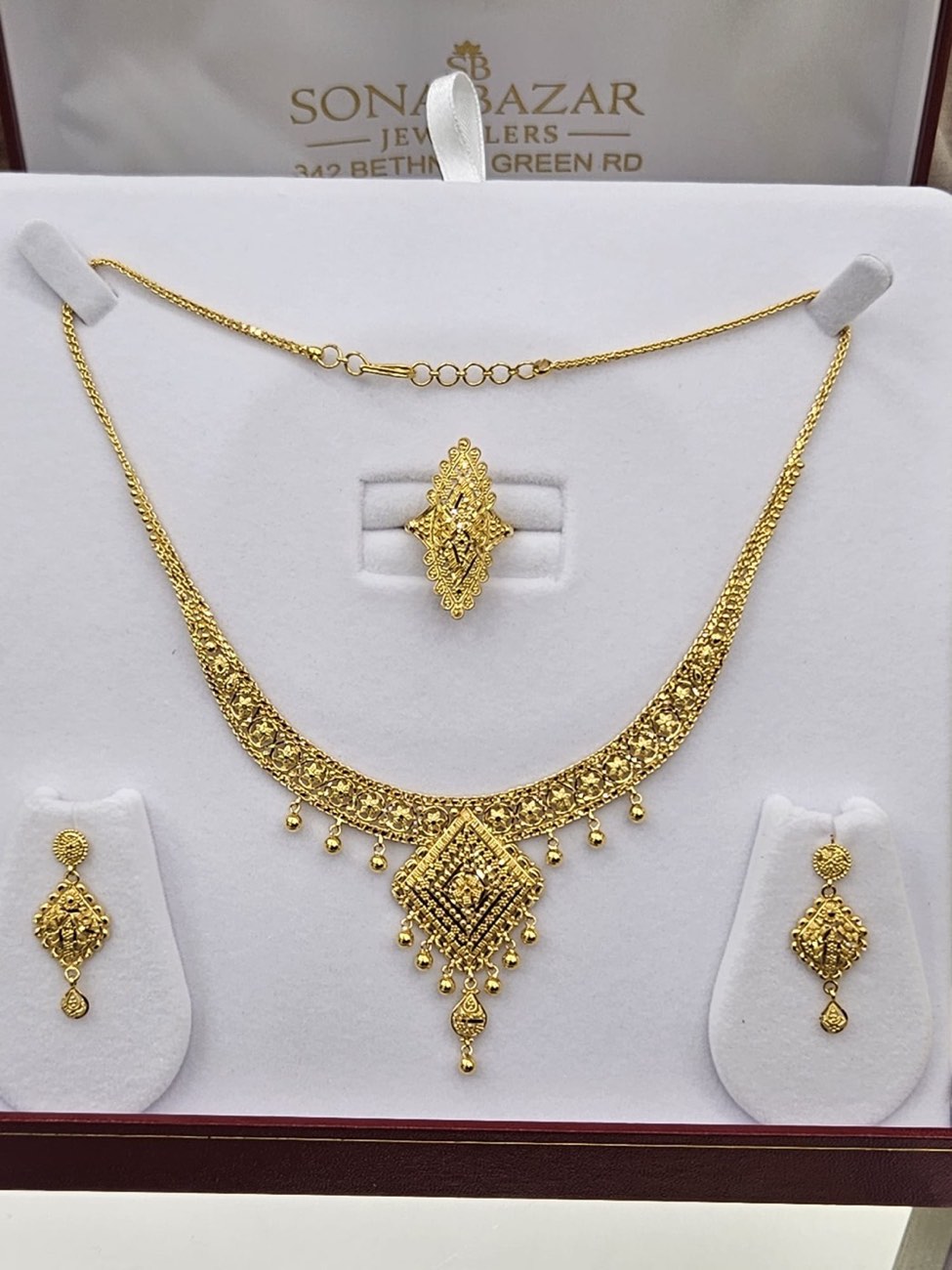 A boxed gold necklace, earring and ring set in a Sona Bazar Jewellers presentation case