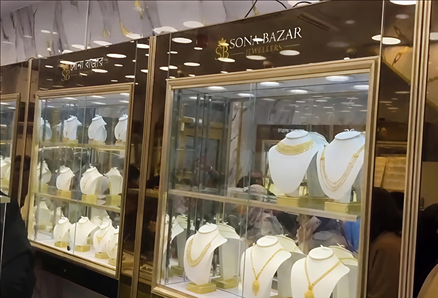 Inside Sona Bazar Jewellers — gold necklaces lit in glass display cabinets beneath the shop's gold logo