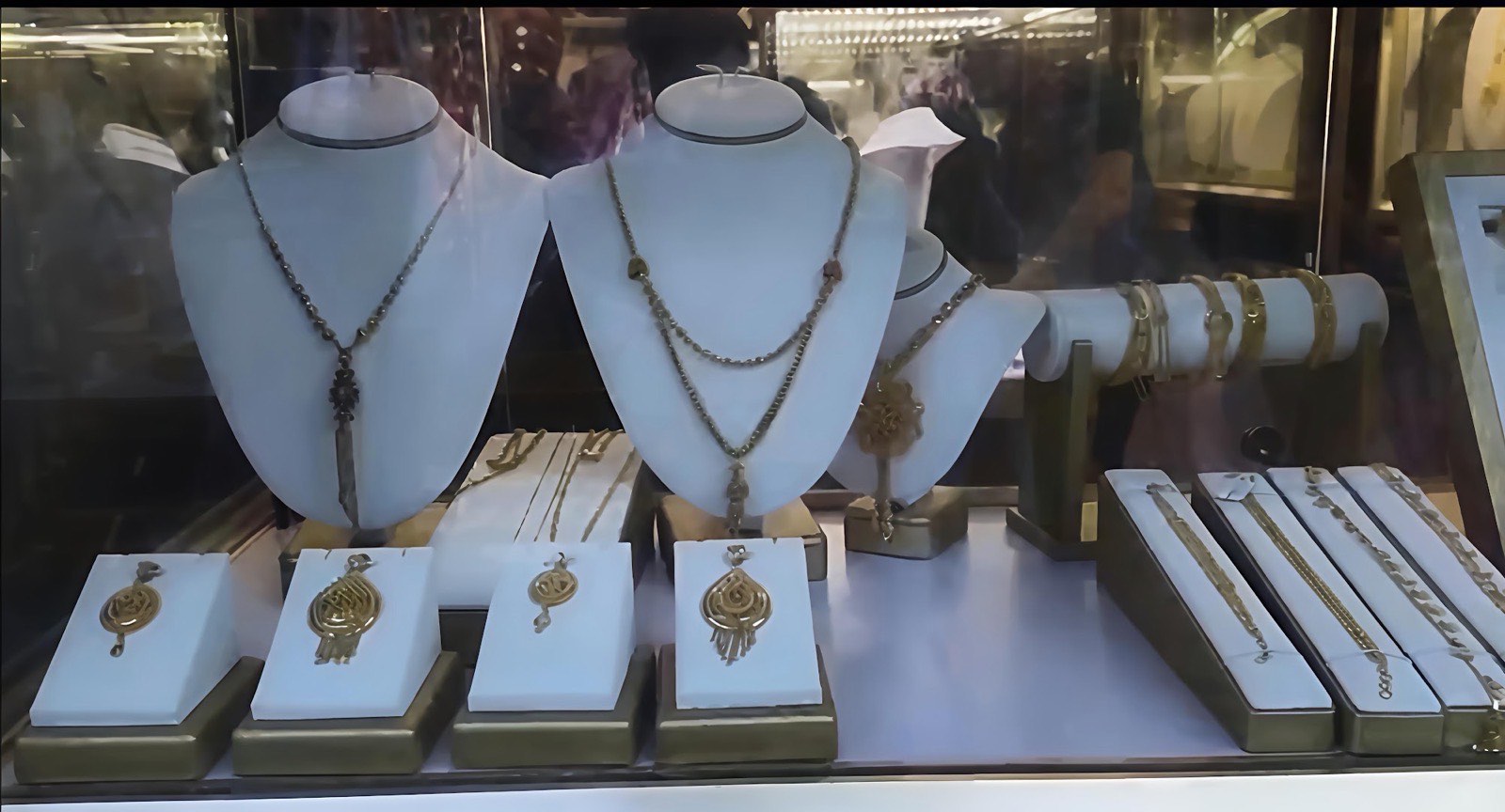 The window display at Sona Bazar Jewellers with gold necklaces, calligraphy pendants and bangles on a bar